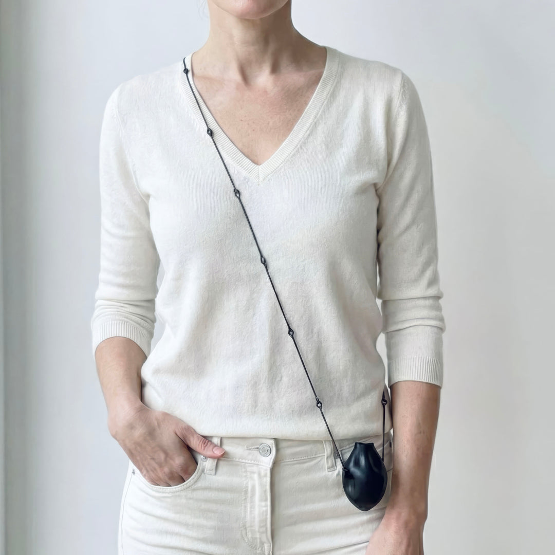 Woman wearing the unique Balloon Necklace in a crossbody style, showing the contrast between the black pendant and industrial iron chain.