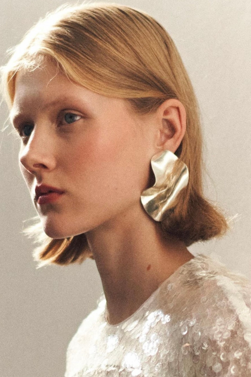 model wears sculptural silver earrings at london fashion week.